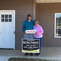 Jan Jacobs with a male client holding a sold sign in front of a recently purchased home